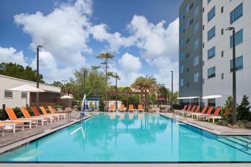 a large swimming pool with chairs and a building at Aloft Orlando at SeaWorld in Orlando