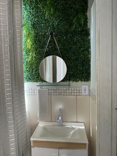a bathroom with a sink and a green wall at Suítes Moinho in Cabo Frio