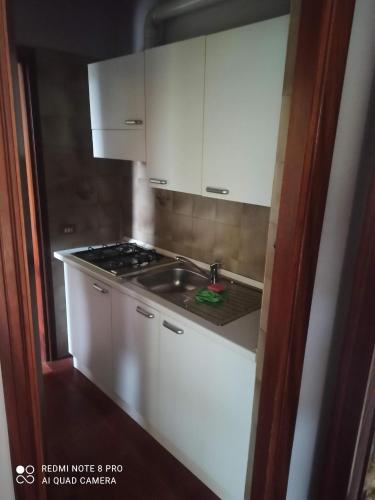 una cocina con armarios blancos y fregadero en Appartamento Bersani, en CastellʼArquato
