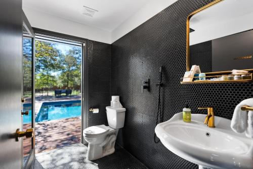 a bathroom with a sink and a toilet and a mirror at Hot Tub + Fire Pit + Pool + Game Room ~ Guesthouse in Manor