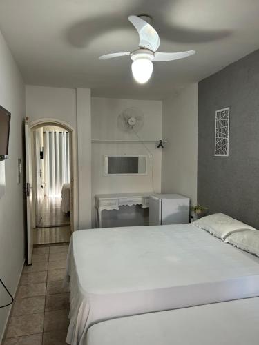 a bedroom with a white bed and a ceiling fan at Suítes Moinho in Cabo Frio