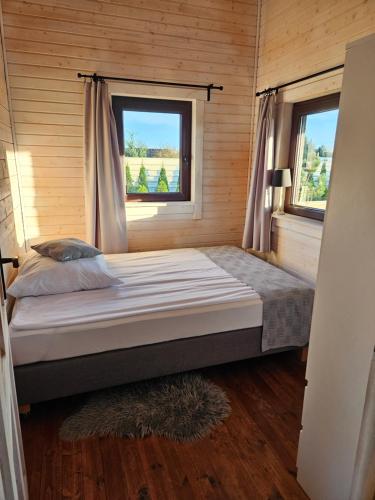 Bett in einem kleinen Zimmer mit zwei Fenstern in der Unterkunft Domek całoroczny MAGJAN z sauną in Złotów