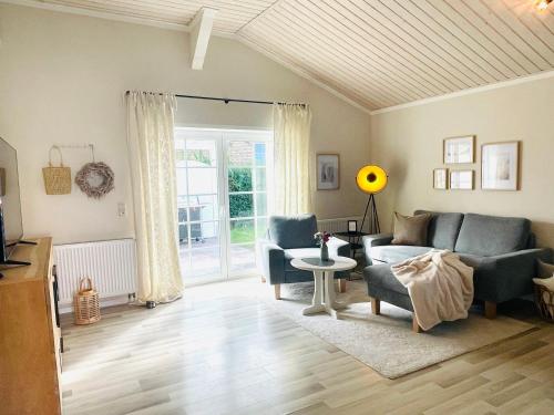 uma sala de estar com um sofá, cadeiras e uma mesa em Strandzone 29 em Kronsgaard