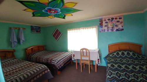 um quarto com 2 camas, uma mesa e uma janela em Dawn House em Ocosuyo