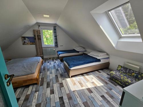 - une chambre mansardée avec 2 lits et une fenêtre dans l'établissement Prázdninový dům Barča Vlkov, à Vlkov