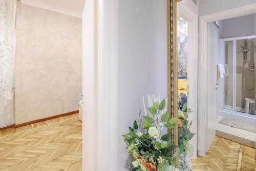 a hallway with a mirror and a vase with flowers at La Vie en Rose in Cuneo