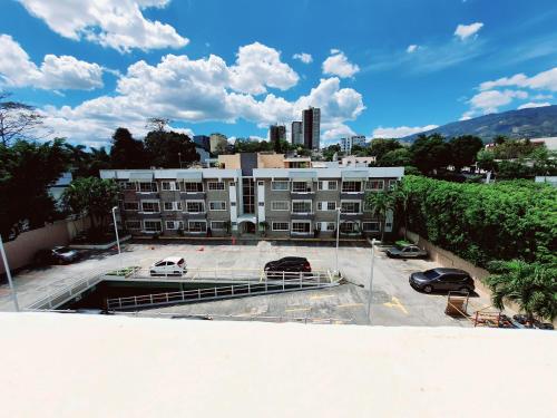duży apartamentowiec z samochodami zaparkowanymi na parkingu w obiekcie SAN BENITO FLATS WIFI 50MG - 4 HUESPEDES - PARQUEOS w mieście San Salvador