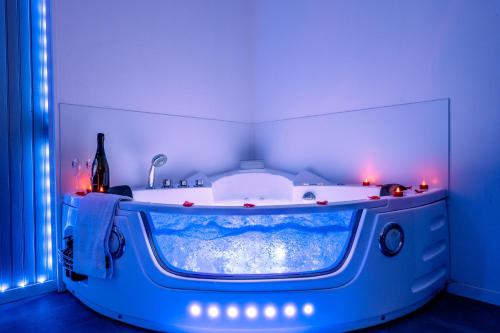 ein Bad mit einer Badewanne in einem Zimmer mit blauen Lichtern in der Unterkunft Suite Romantique in Sault-de-Vaucluse