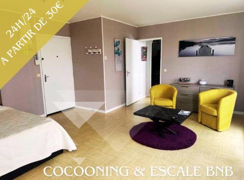a bedroom with a bed and two yellow chairs and a table at Cocooning Home in Châteauroux