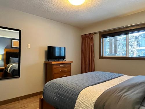 sypialnia z łóżkiem, telewizorem i oknem w obiekcie Perfect family 2-bed Condo with hot tub w mieście Dead Man's Flats