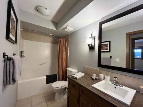a bathroom with a sink and a toilet and a mirror at Perfect family 2-bed Condo with hot tub in Dead Man's Flats
