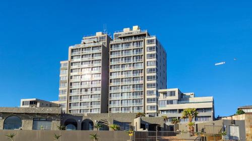 a tall building with a blue sky in the background at Infinity LG8 Beachfront Apartment in Bloubergstrand