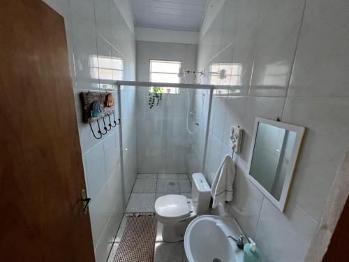 a white bathroom with a toilet and a sink at Chácara Bela Vista in Paraibuna