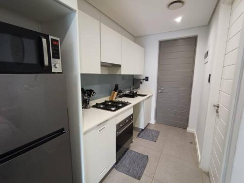 a white kitchen with a stove and a microwave at Modern comfy studio apartment with pools in Umhlanga
