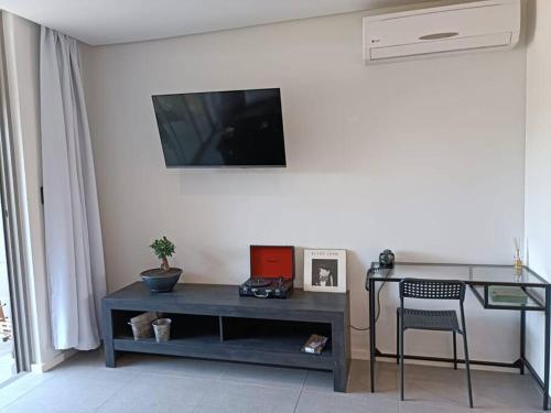 a living room with a table and a television on a wall at Modern comfy studio apartment with pools in Umhlanga