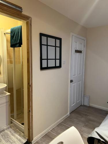 ein Badezimmer mit einem Waschbecken, einem Spiegel und einer Tür in der Unterkunft Oxborne Rooms UK - Seaton in London