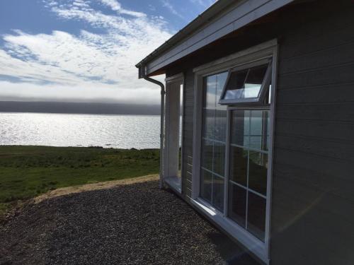 a window on the side of a building next to the water at Mörk Superior Cottages in Hvammstangi
