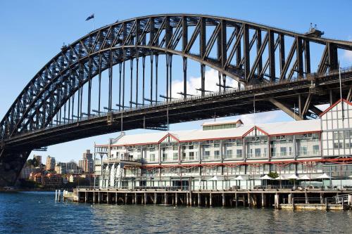 a bridge over the water with a building under it at Pier One Sydney Harbour, Autograph Collection in Sydney