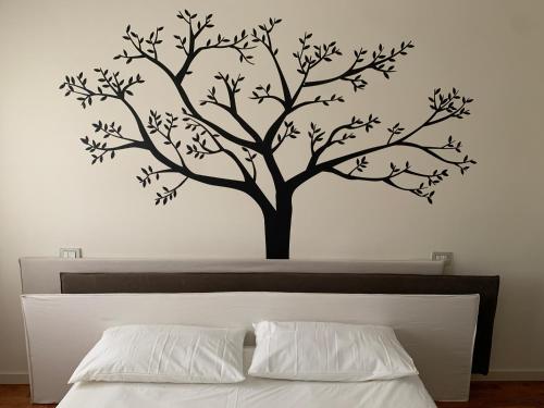un albero con foglie su una parete bianca sopra un letto di Casa Giulia a SantʼArcangelo di Romagna