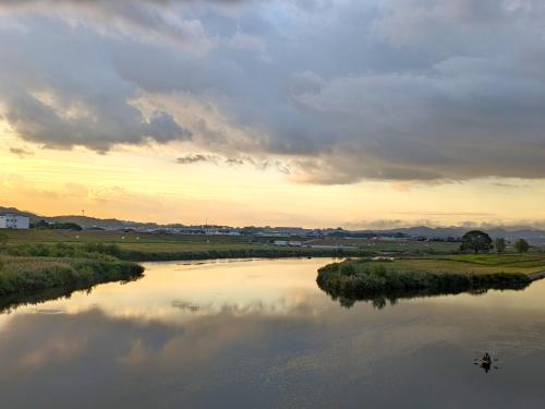 a person in a boat on a river at sunset at Plaza Hotel Nogata in Nōgata