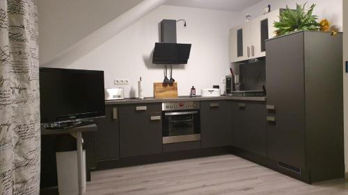 a kitchen with brown cabinets and a tv and a counter at Ferienresidenz Kap Arkona - Whn. 15 - in Putgarten
