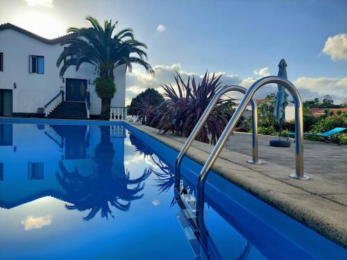 a swimming pool with blue water and palm trees at La Finca de Ananás - House in Ponta Delgada