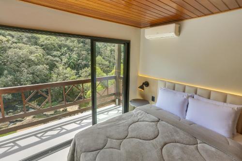 um quarto com uma cama e uma grande janela em Pousada Alpenhof em São Pedro de Alcântara