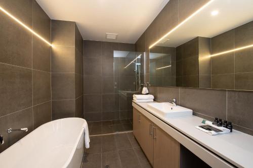 a bathroom with a bath tub and a sink at Rydges Pit Lane in Tailem Bend