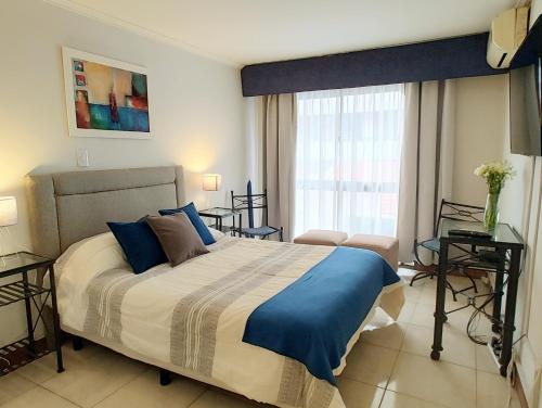 1 dormitorio con 1 cama grande con almohadas azules en MENDOZA SUITES en Mendoza