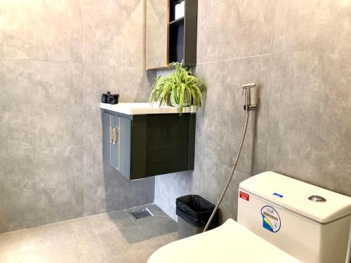ein Badezimmer mit einem WC und einer Pflanze auf einer Theke in der Unterkunft The Nam’s House-Nha Trang in Nha Trang
