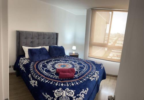 a bedroom with a blue and white bed with a window at Apartamento en Metro Ñuble in Santiago