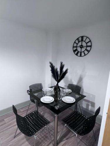 a dining room table with chairs and a clock on the wall at Broad street - Balcony 1 bedroom apartment in Birmingham