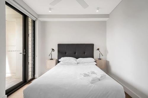 シドニーにあるStylish 2BR Top-Level Unit with Lift near Bondi Beachの大きなベッドと窓のある白い寝室