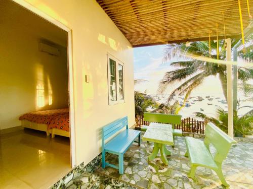 a room with chairs and a table and a bedroom at Homestay BONO Mũi Né in Phan Thiet