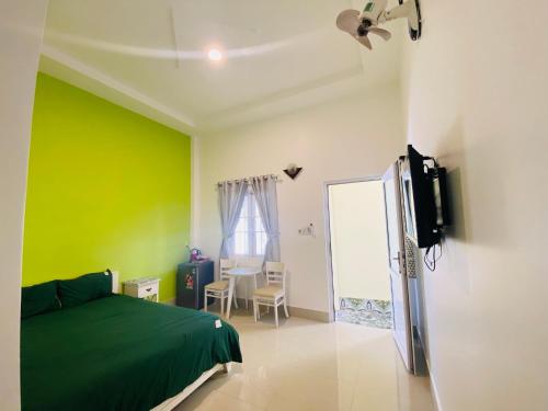 1 dormitorio con paredes verdes, 1 cama y TV en Homestay BONO Mũi Né, en Phan Thiet