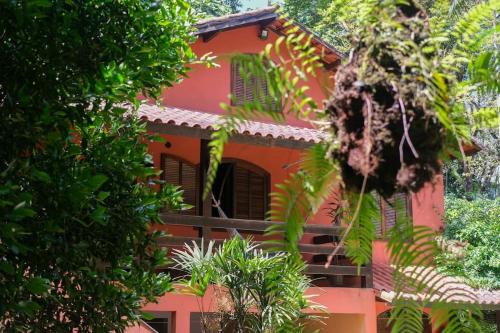 un edificio rojo con árboles delante de él en Casa em penedo com cachoeira en Penedo