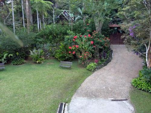 a garden with a bench and flowers and plants at Casa em penedo com cachoeira in Penedo
