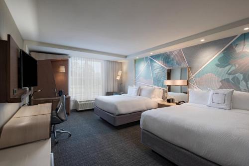 a hotel room with two beds and a flat screen tv at Courtyard by Marriott Jackson Madison in Madison