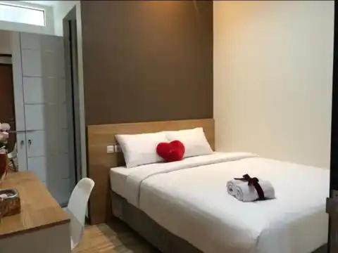 a bedroom with a white bed with a red heart on it at Phoenix Guest House in Surabaya