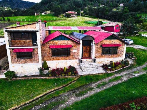 una casa con tetti rossi su un campo verde di Brisas de San Roque by Rotamundos a Monguí