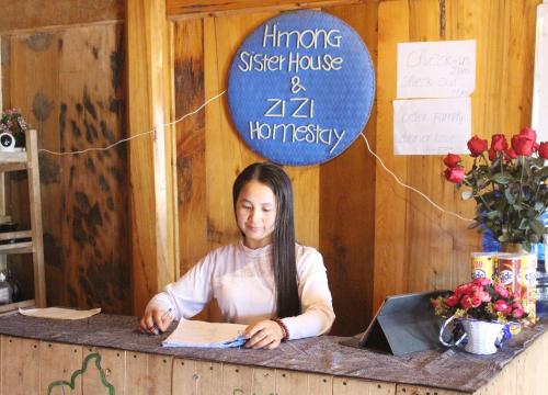 a woman sitting at a counter in a room at Hmong Sister House and Trekking in Sa Pa