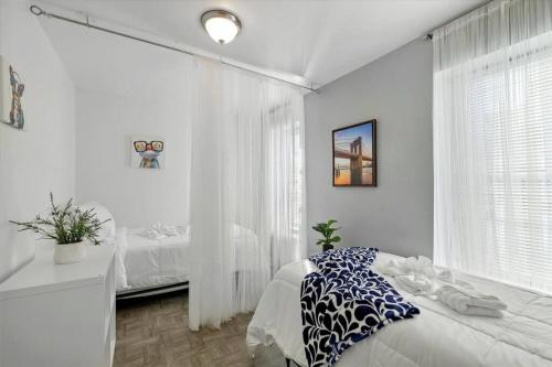 a white bedroom with a bed and a window at Modern 2 Bdrm 10 Mins Metro To City Center in Philadelphia