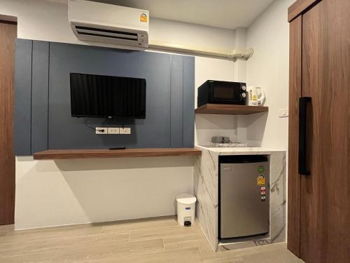a room with a refrigerator and a tv on a wall at Rendezvous Oldtown Chiangmai in Chiang Mai