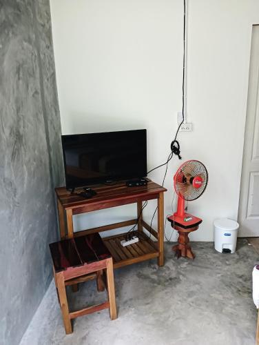 une télévision assise au-dessus d'une table avec un ventilateur dans l'établissement lungpeiykhomestay house, à Ban Bang Bao