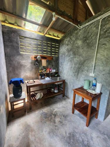 a kitchen with a table and two tables in a room at lungpeiykhomestay house in Ban Bang Bao