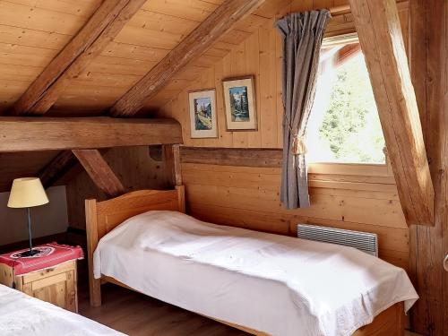 ein Schlafzimmer mit einem Bett in einer Blockhütte in der Unterkunft Ferme Chalet rénovée 3 étoiles à Cordon - FR-1-560-102 in Cordon