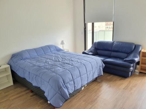 a bedroom with a blue bed and a couch at Cordoba y Florida, Cordoba 618 in Buenos Aires