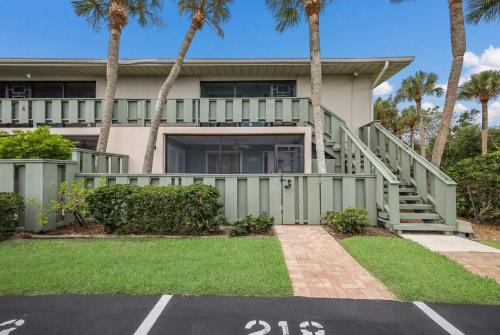 a house with a green fence and palm trees at West Bay Cove 218 condo in Holmes Beach