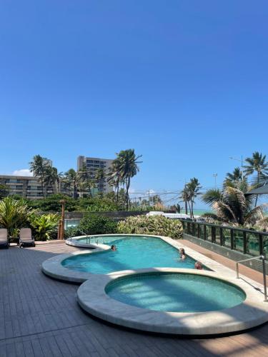 une piscine dans un complexe hôtelier avec des gens dedans dans l'établissement Coral Ritz - Flat beira mar (Condomínio Ritz Suites Home Service), à Maceió