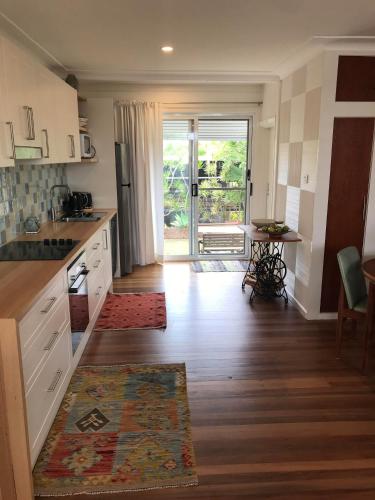 a kitchen with white cabinets and a door to a patio at Shelly Beach Townhouse in East Ballina